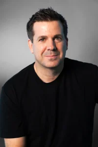 Portrait phot of Brian Pilgrim wearing a black shirt, grey background behind him